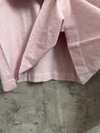Light pink long-sleeve top hem with subtle brand text near waistband
