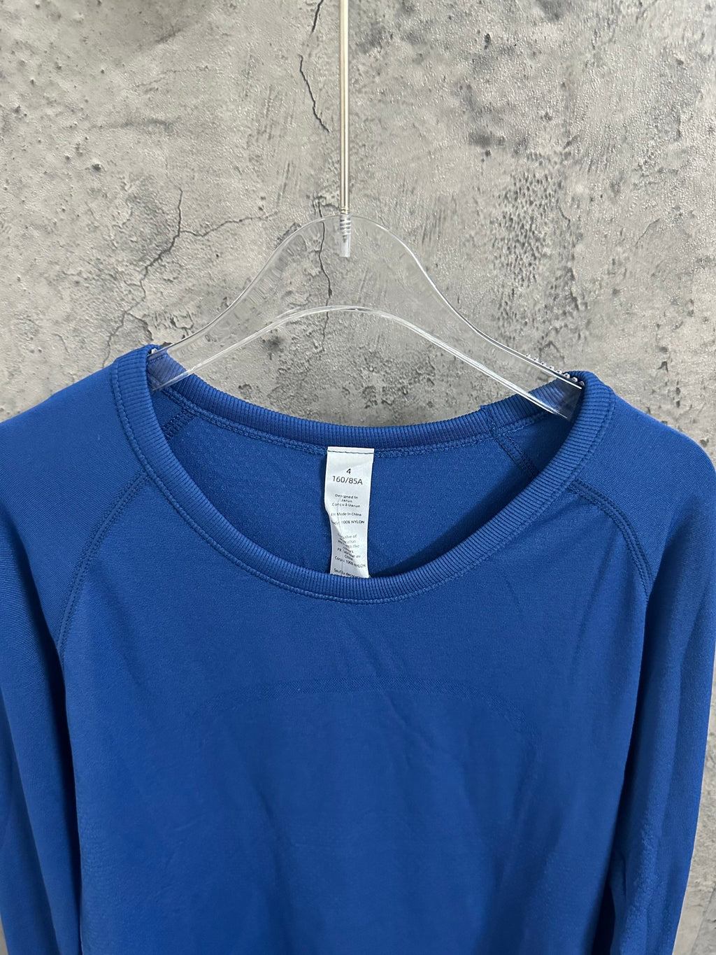 Blue crewneck long-sleeve T-shirt with ribbed collar and white tag.