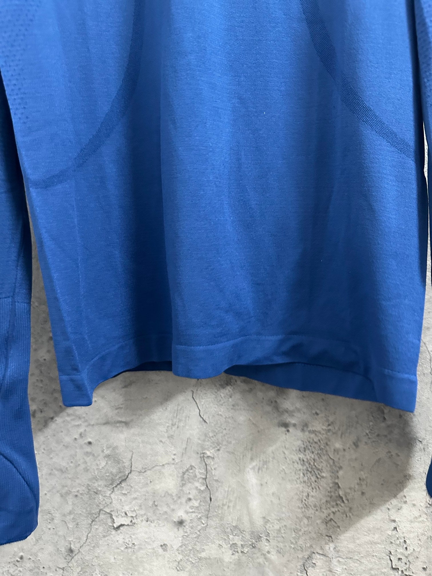 Blue long-sleeve T-shirt hem with curved bottom and underarm seam.
