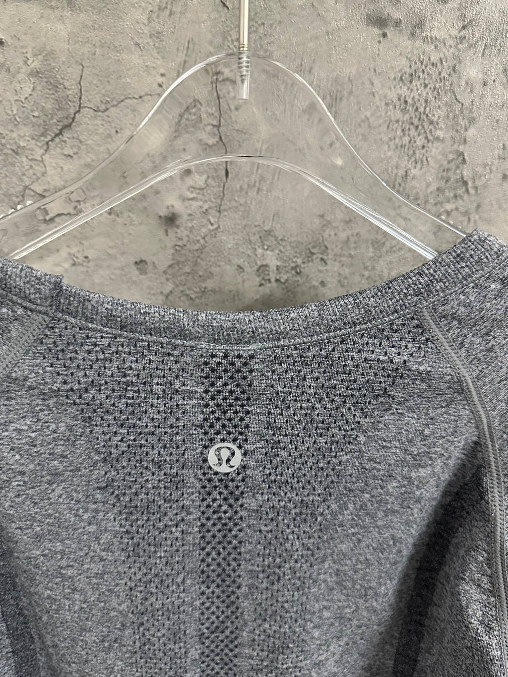 Back of heather gray long-sleeve knit top with small circular logo at center