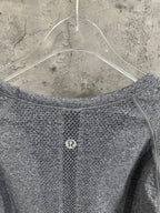 Back of heather gray long-sleeve knit top with small circular logo at center