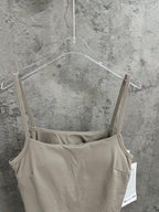 Light beige romper front with spaghetti straps and small circular chest logo