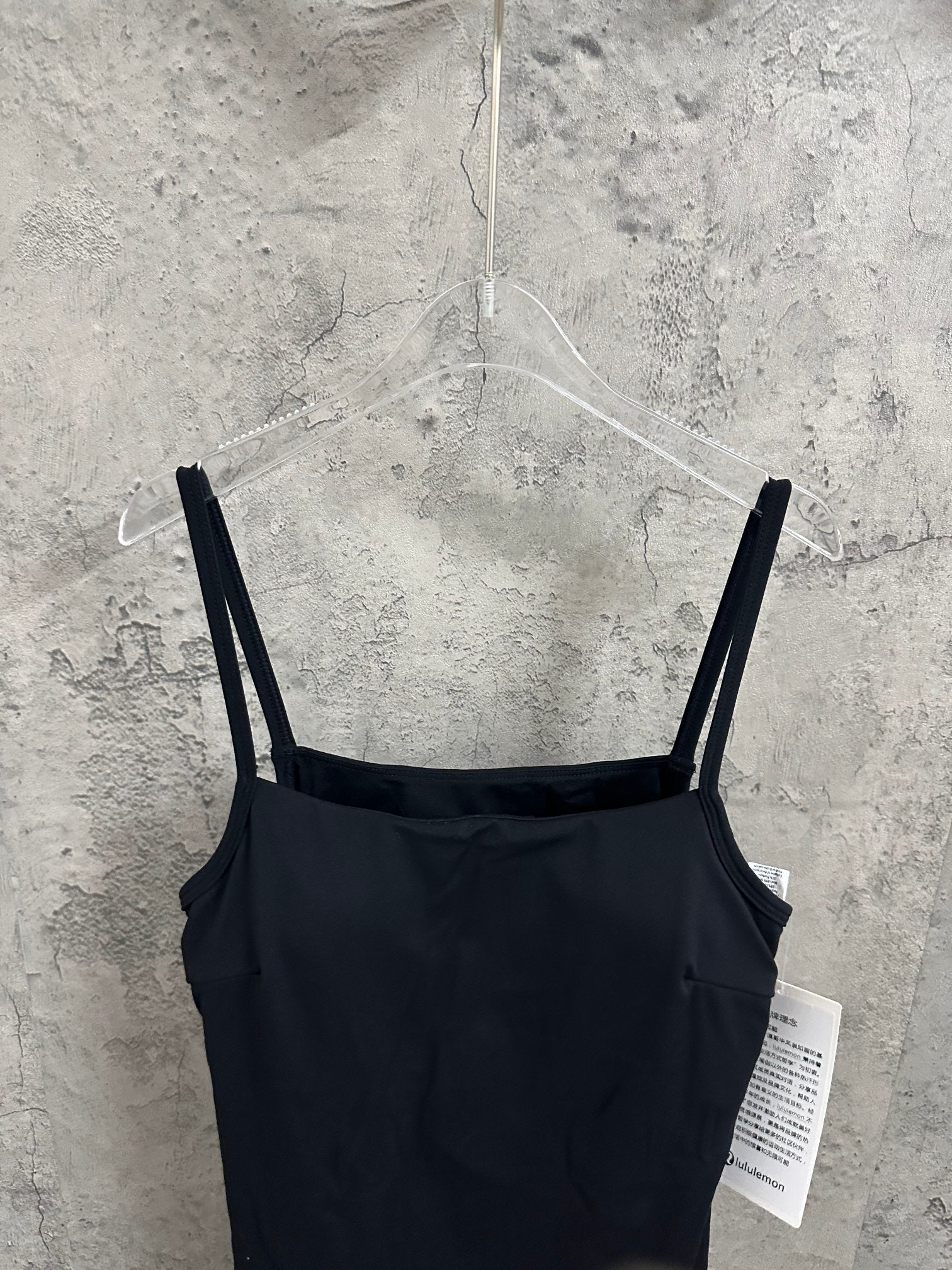 Black spaghetti-strap dress viewed from back with straight shoulder straps on hanger.