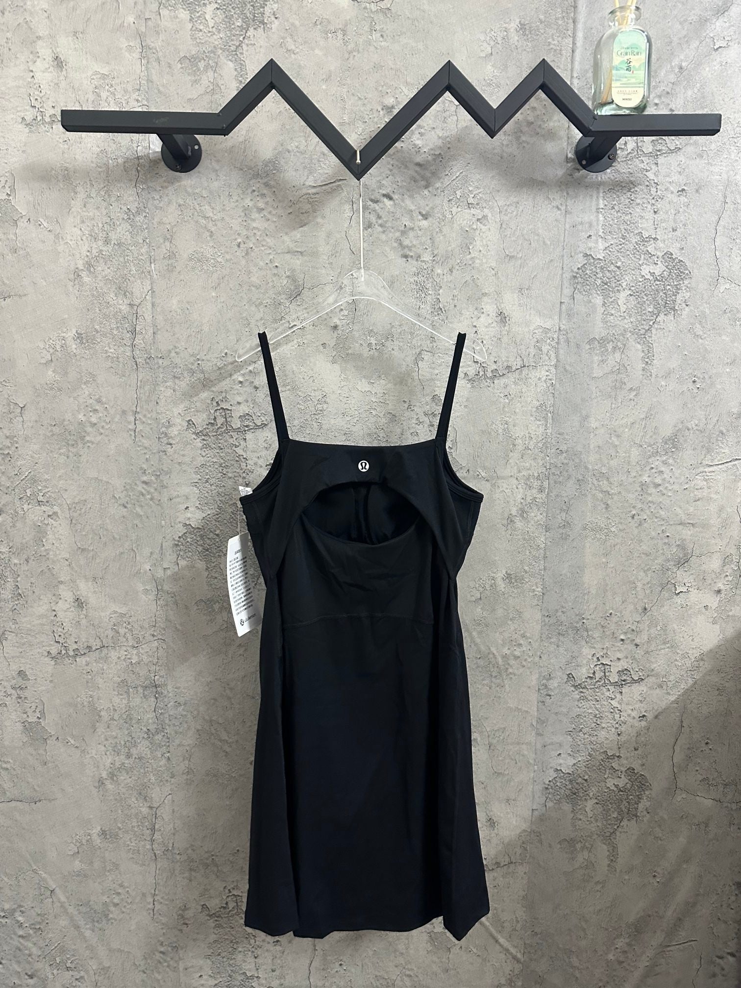 Black spaghetti-strap dress with square neckline and slightly flared skirt on hanger.
