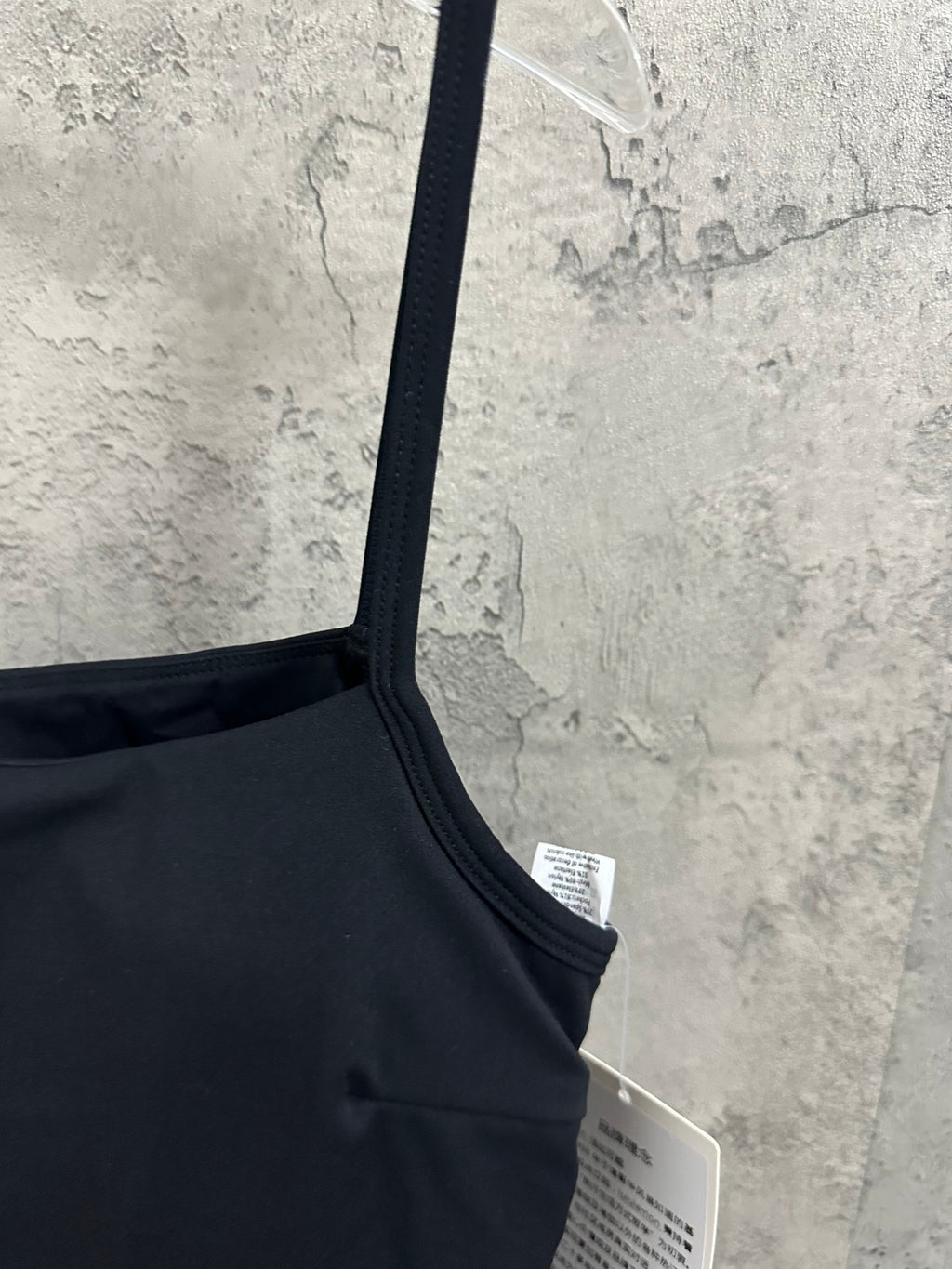 Black spaghetti-strap dress shoulder detail with white tag