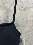 Black spaghetti-strap dress close-up of shoulder strap and neckline seam with tag.