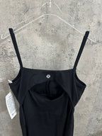 Black spaghetti-strap dress front close-up showing gathered bust and small logo detail.