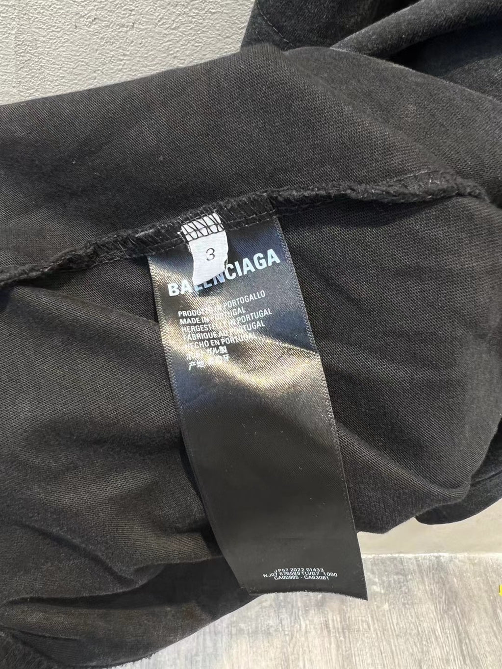 Balenciaga T-shirt care label and fabric tag on dark charcoal hem