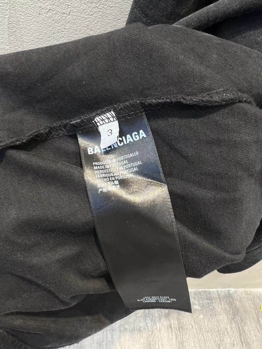 Balenciaga T-shirt care label and fabric tag on dark charcoal hem