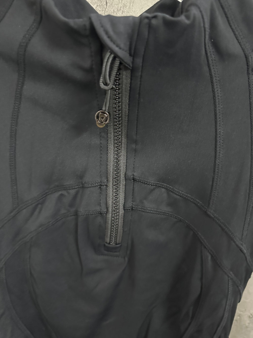 Dark jacket close-up of quarter-zip placket with metal zipper pull