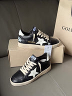 Black low-top sneakers with white star logo and white laces, beige outsole