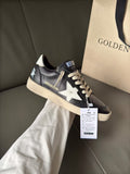 Black low-top sneakers with white star patch, beige sole, lace-up front