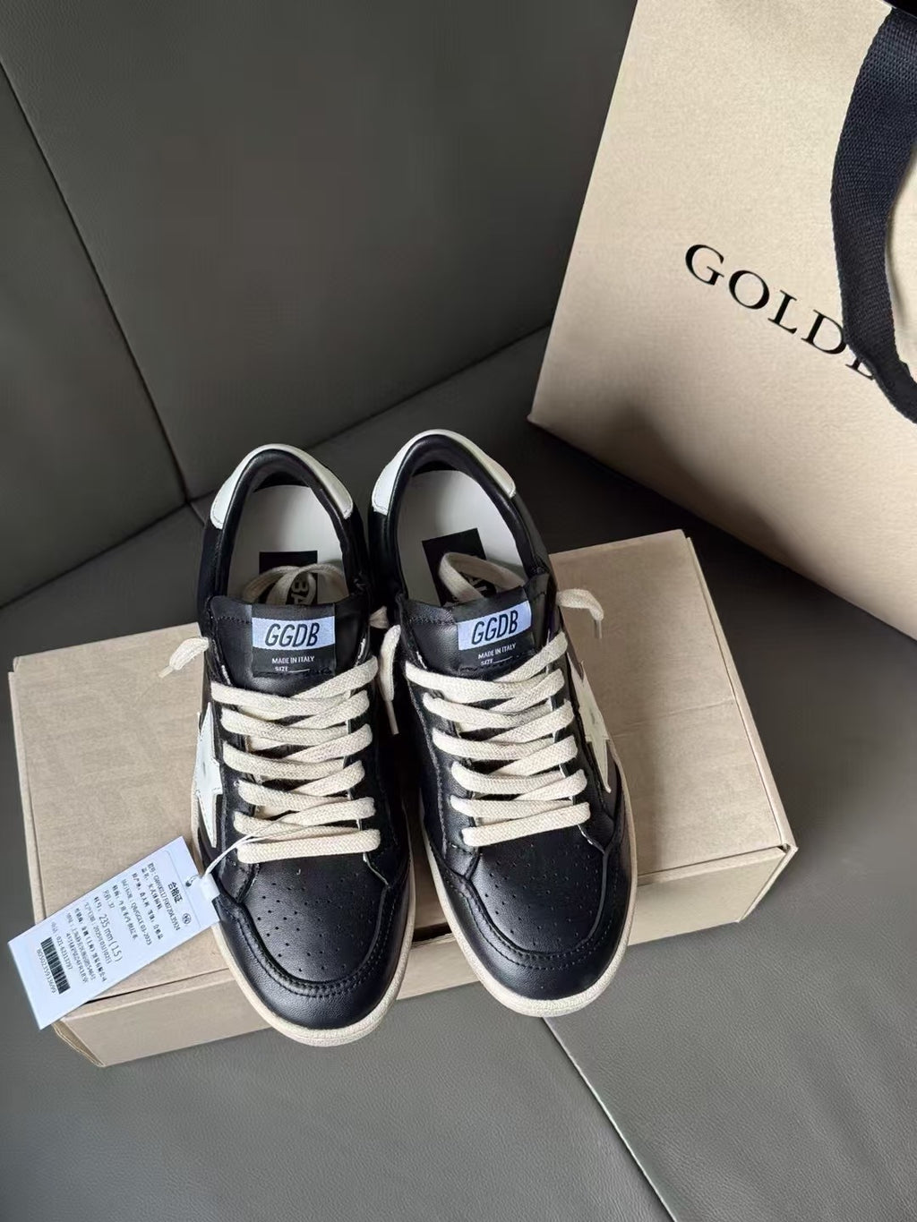 Pair of black lace-up sneakers with white star detail and beige rubber soles