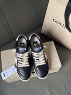 Pair of black lace-up sneakers with white star detail and beige rubber soles