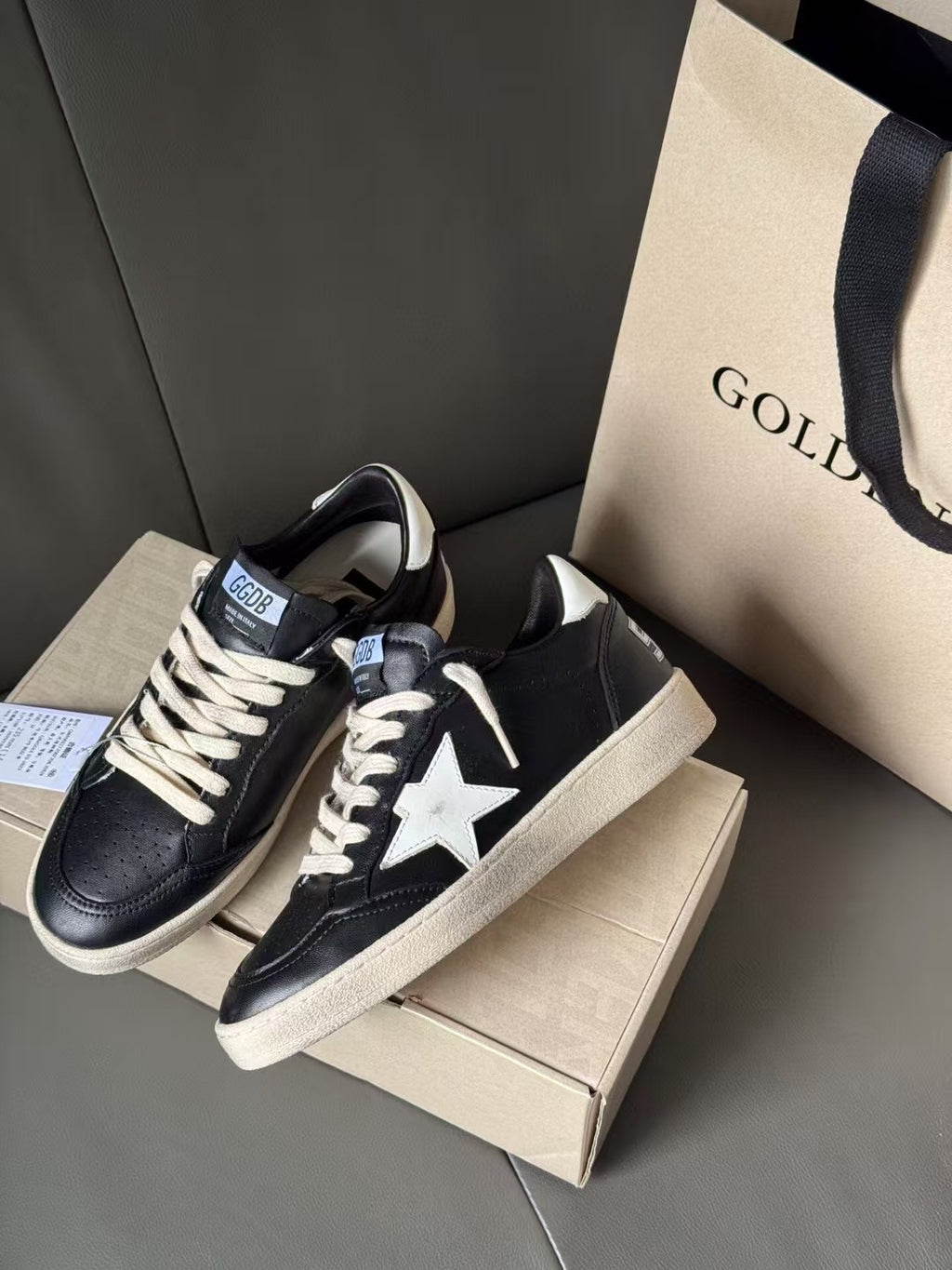 Black lace-up sneakers with white star emblem and beige sole, side angle