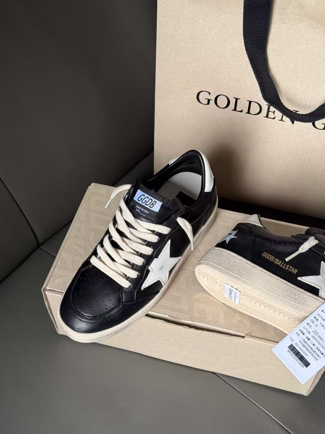 Black sneakers with white star side panel, beige sole, laces tied