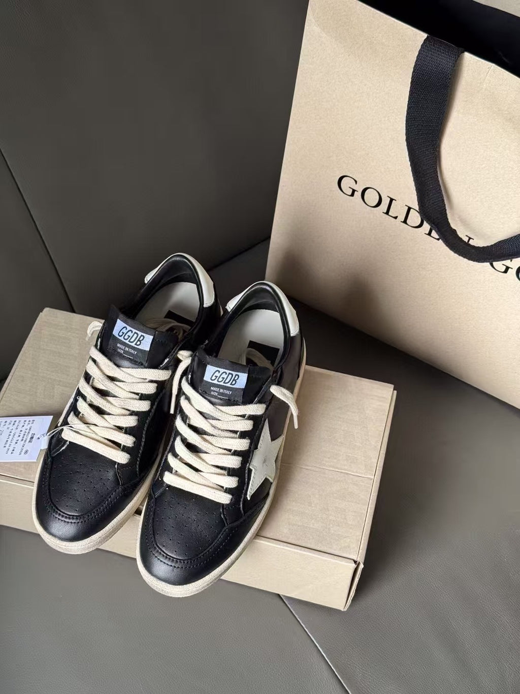 Black pair of lace-up sneakers with white star detail and beige rubber soles