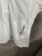 White jacket sleeve with pocket flap and metal zipper pull, drawstring cord