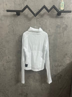 White zip-up jacket with high collar and chest logo patch, long sleeves