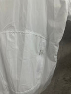 White jacket side/back panel close-up with curved seam and small zip pocket