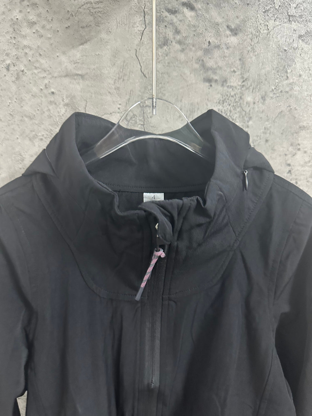 Black hooded jacket chest close-up with hidden zipper and drawstring pull