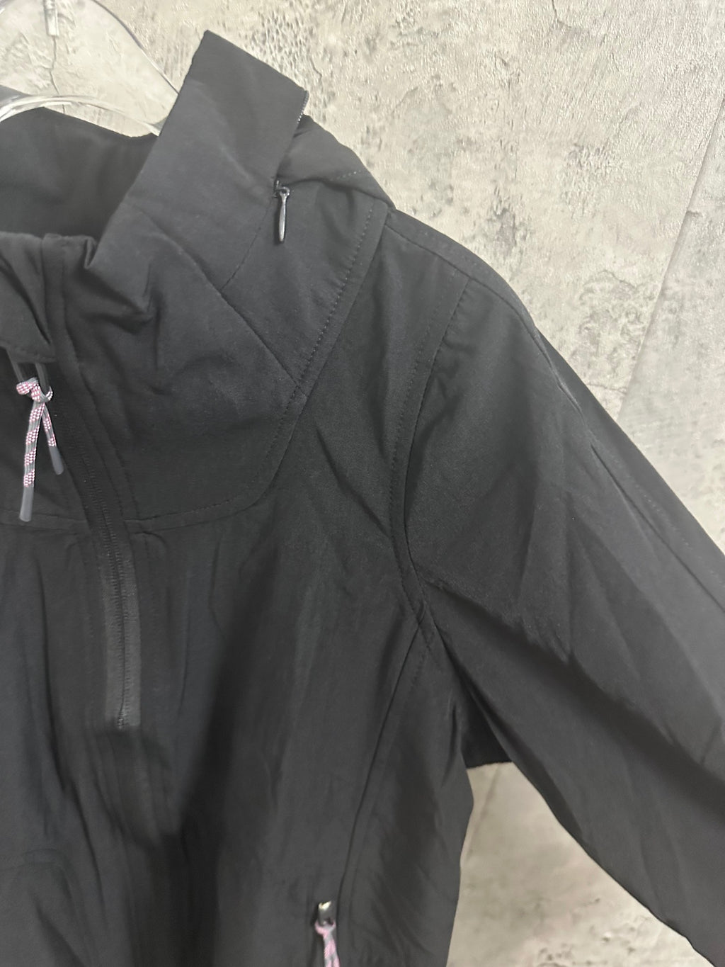 Black hooded jacket angled side view with zip pocket detail