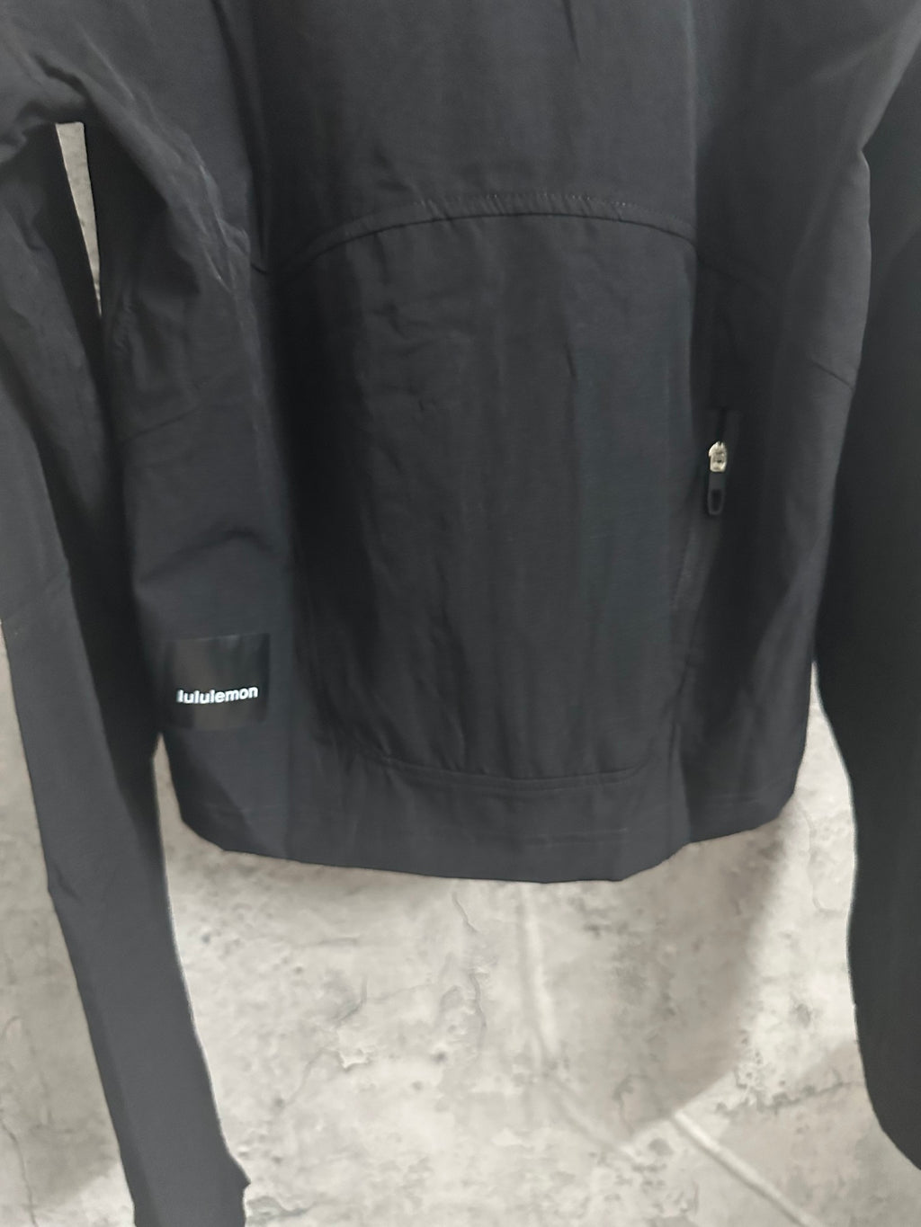 Black hooded jacket front panel close-up with small logo label