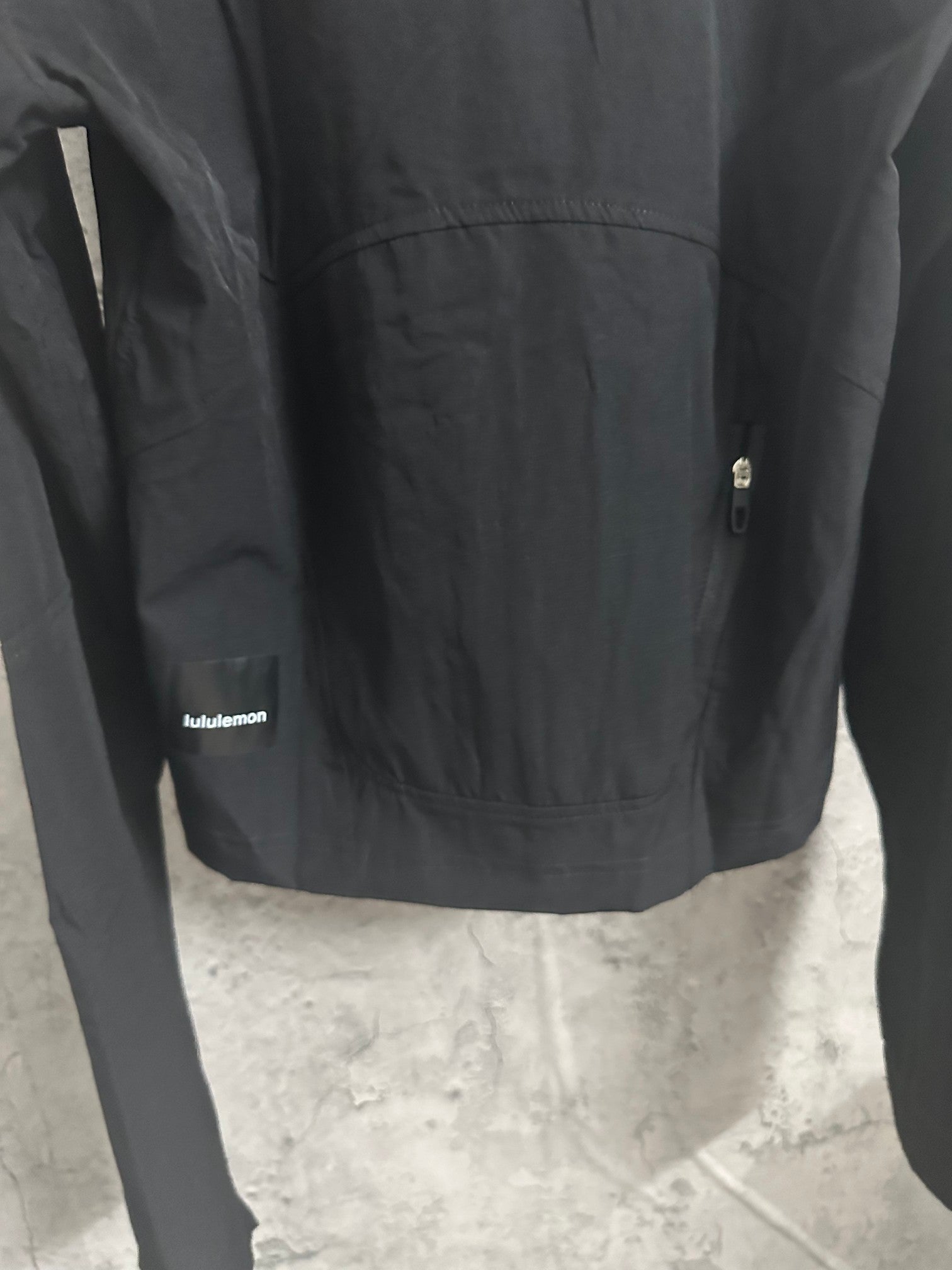 Black hooded jacket with logo label at hem and small metal zipper