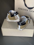 Golden Goose sneakers showing heel: gold glitter upper with black lace details