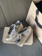 Golden Goose low-top sneakers with gold glitter overlays and black laces, white sole