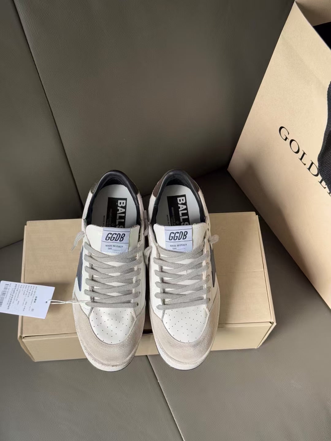 White lace-up sneakers with blue star side, gray tongue labels, on shoebox