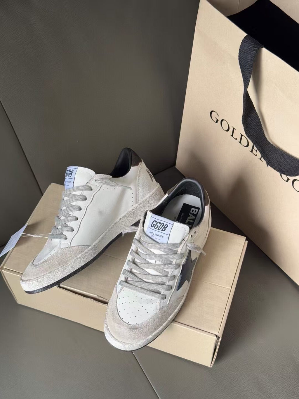 Pair of white low-top sneakers with blue star side panels, lace-up, on shoebox
