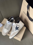 White leather sneakers with blue star and gray trim, lace-up, shown on shoeboxes