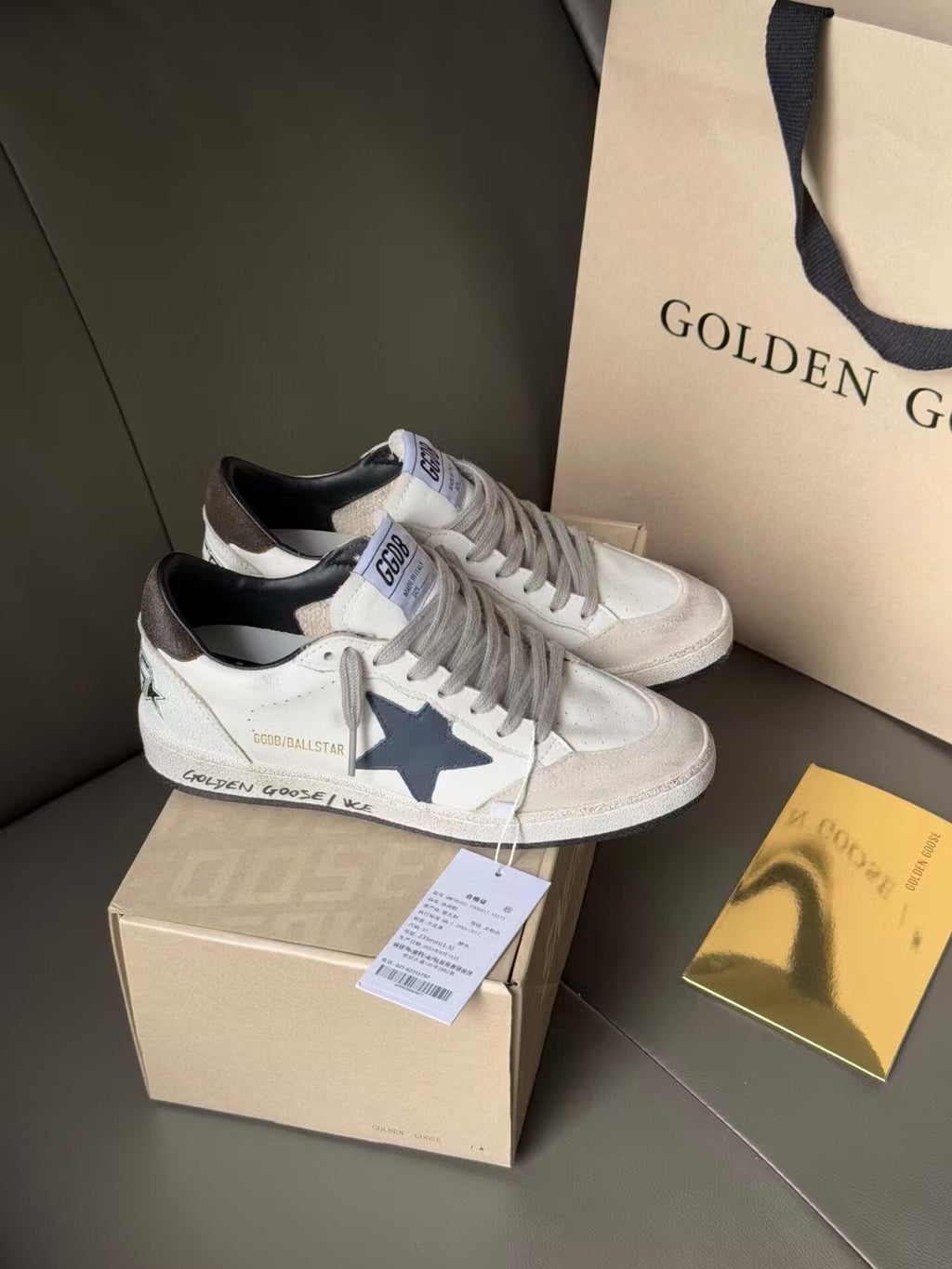 White lace-up sneakers with blue star on side, perforated toe, on shoebox