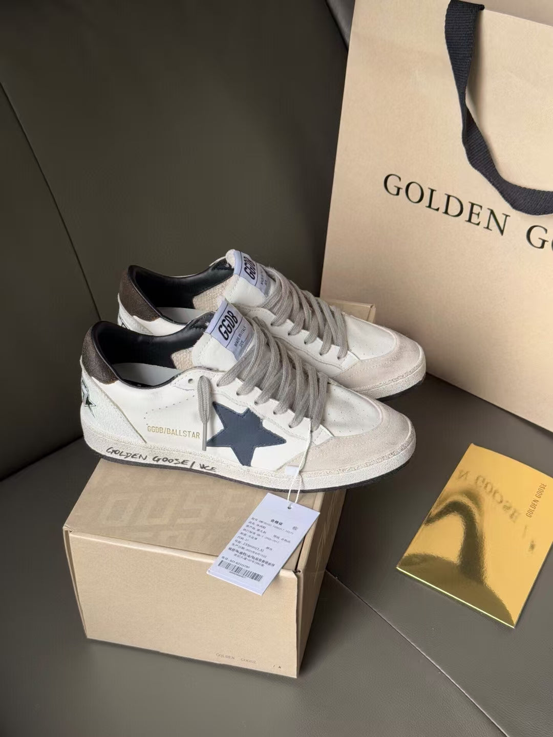 White lace-up sneakers with blue star on side, perforated toe, on shoebox
