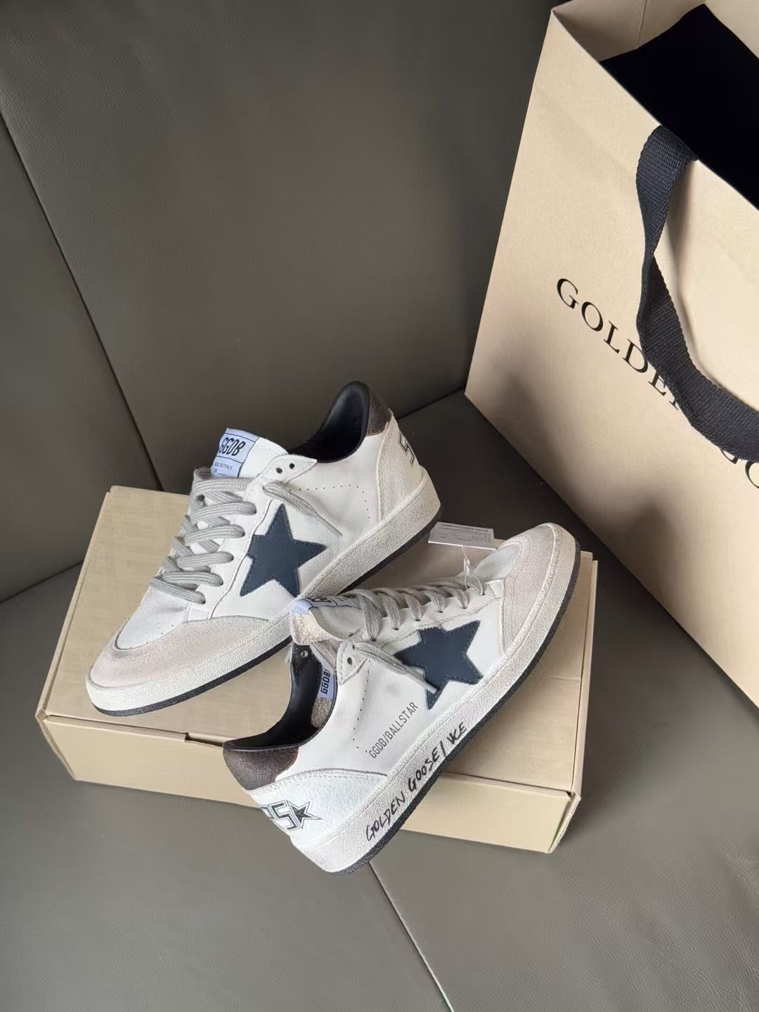 White low-top sneakers with blue star on side, gray laces, on shoebox