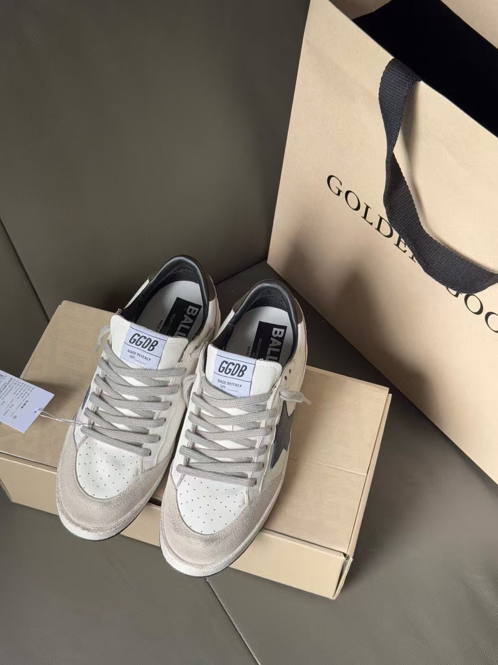 White lace-up sneakers with blue star side panels, perforated toe, on shoebox