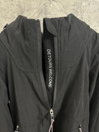 Black hooded jacket with DETOURS WELCOME text tape on zip placket