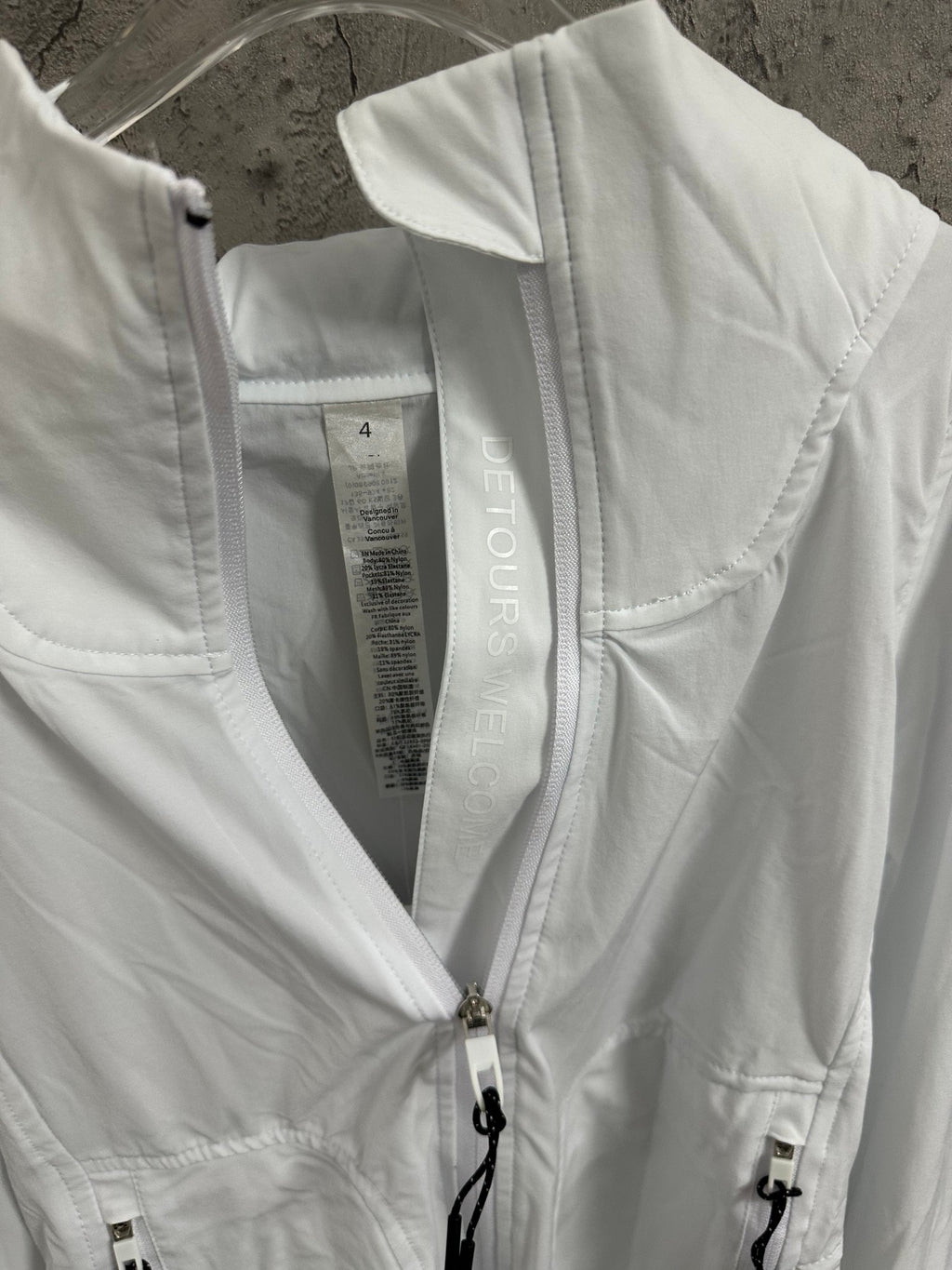 White jacket interior view with neck label and front zipper with drawstring cord