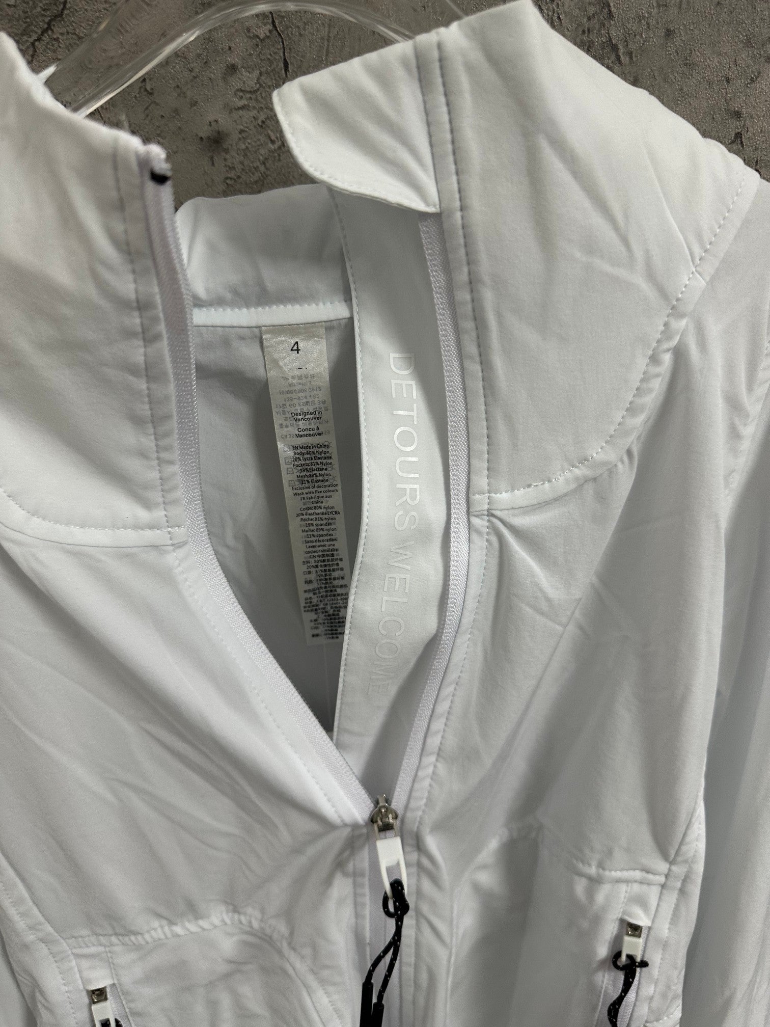 White hooded jacket interior label view with front zipper and drawstring cord