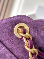 Gold-toned ring clasp on purple suede bag with engraved badge