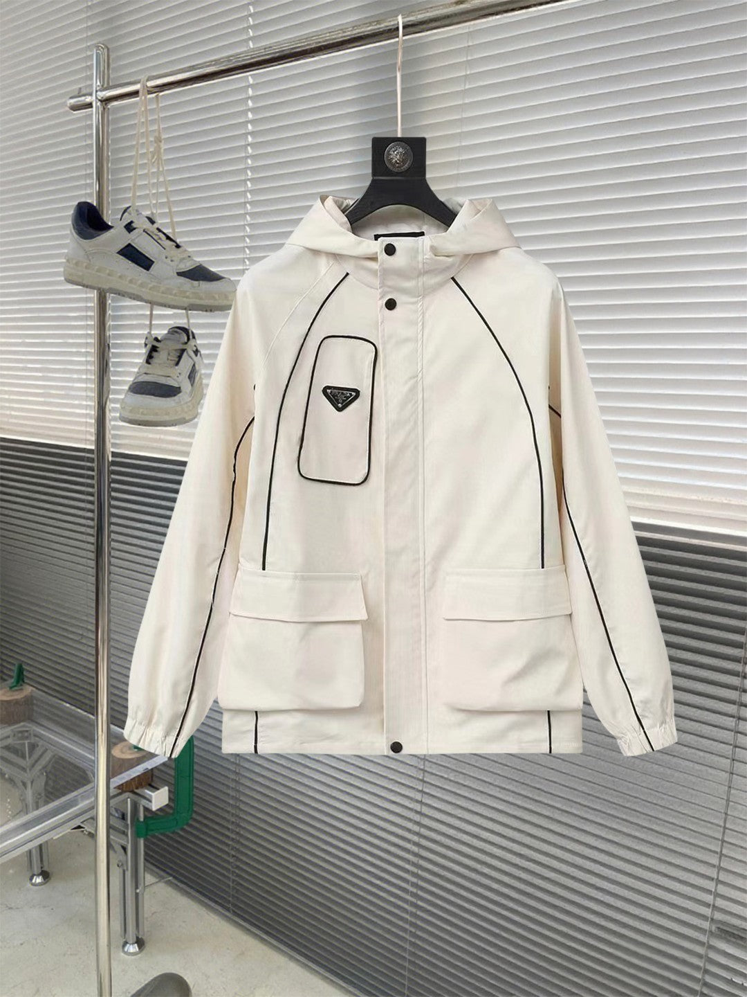 White hooded jacket with front buttons, large pockets, and triangular logo patch