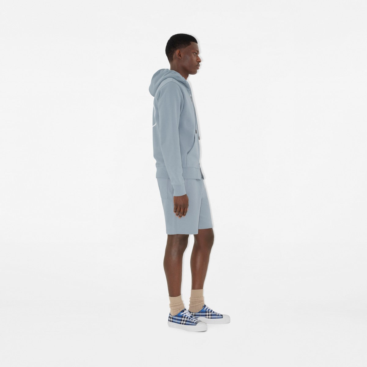 Plaid sneakers on feet with beige socks, blue laces and white rubber sole