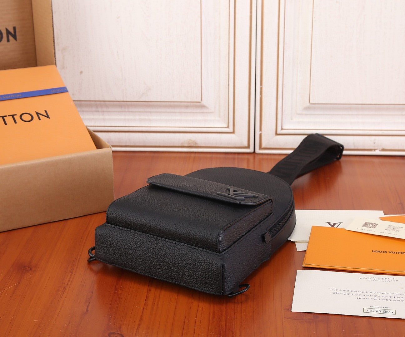 Men's Louis Vuitton mini sling bag, black textured leather, flap pocket and carry strap.