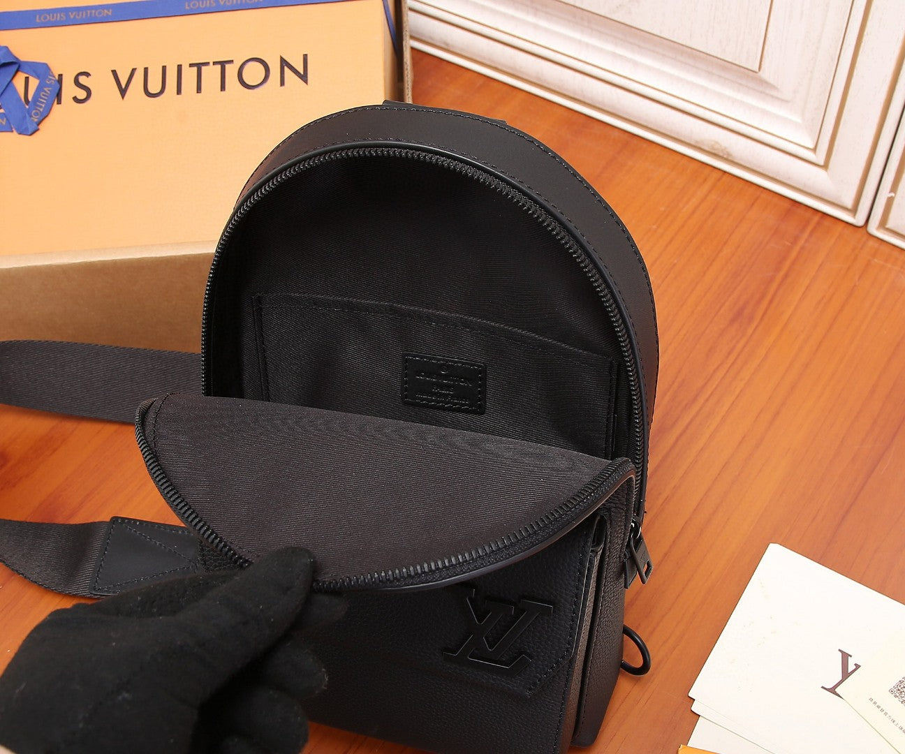 Men's Louis Vuitton mini sling bag with open flap, textured lining and LV logo.