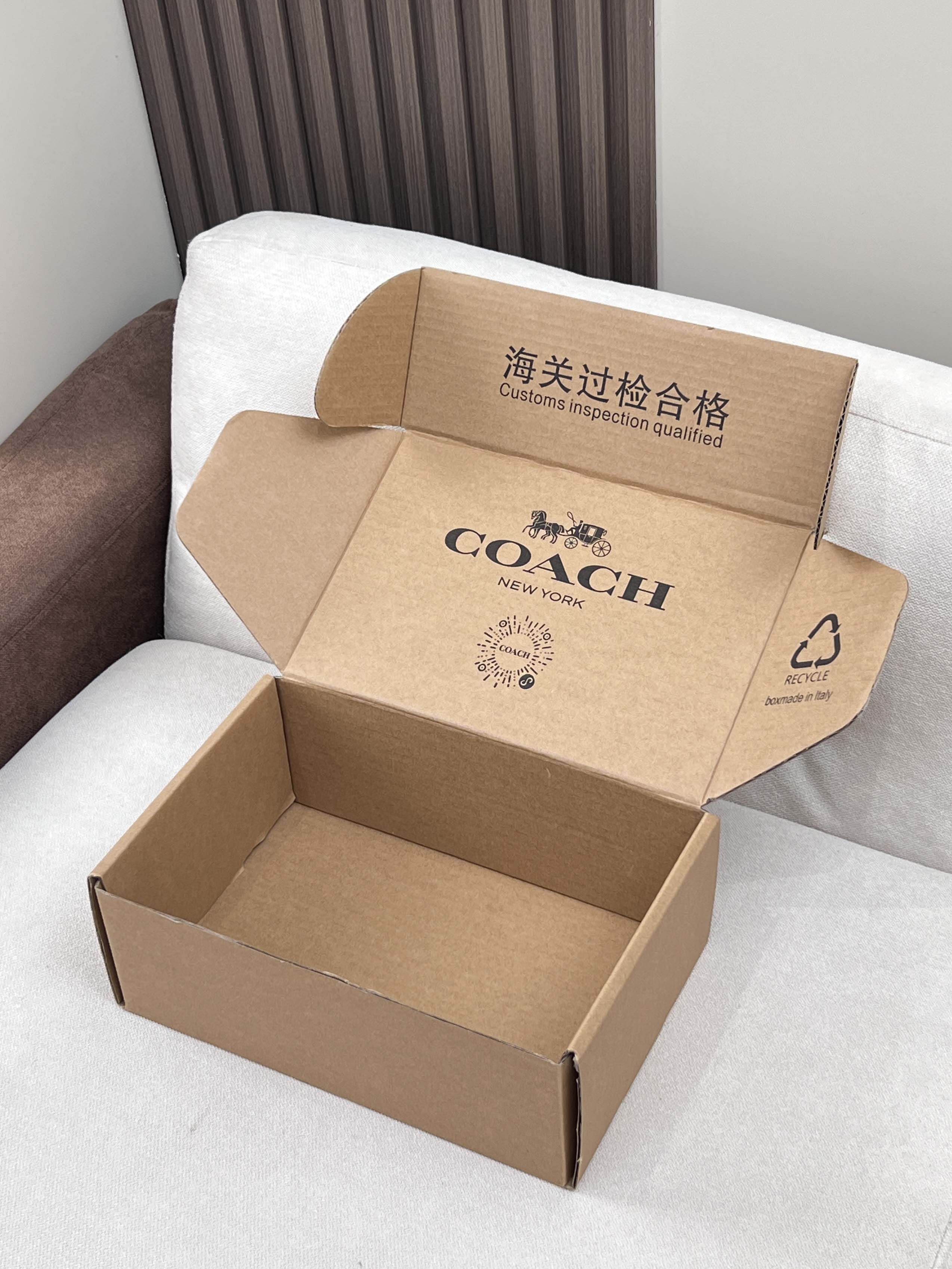 Opened cardboard gift box with COACH logo and inspection label