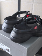 Black platform sandals with bow straps and heart accents on the side