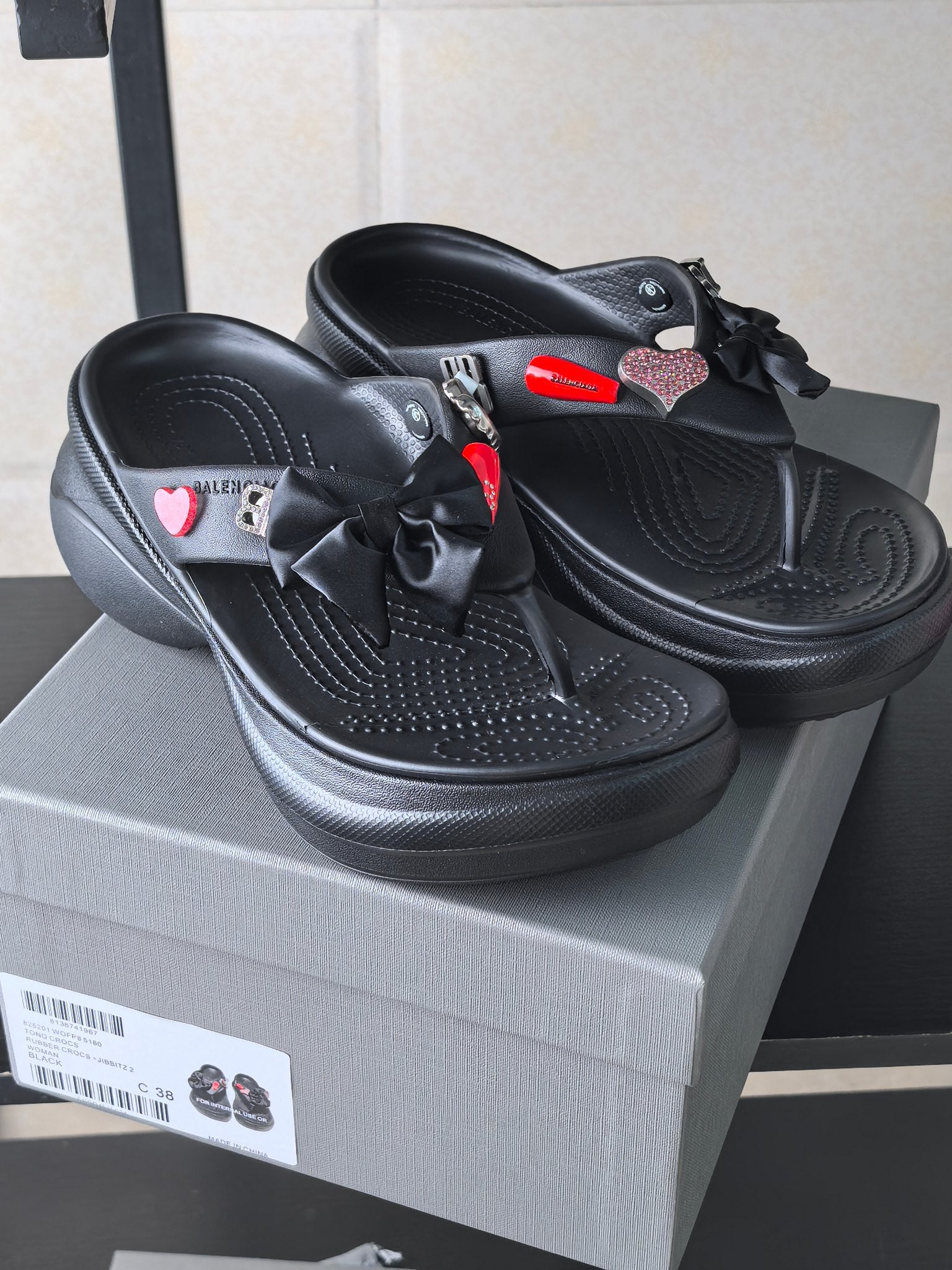 Black platform sandals with ribbon bows and heart patches on the uppers