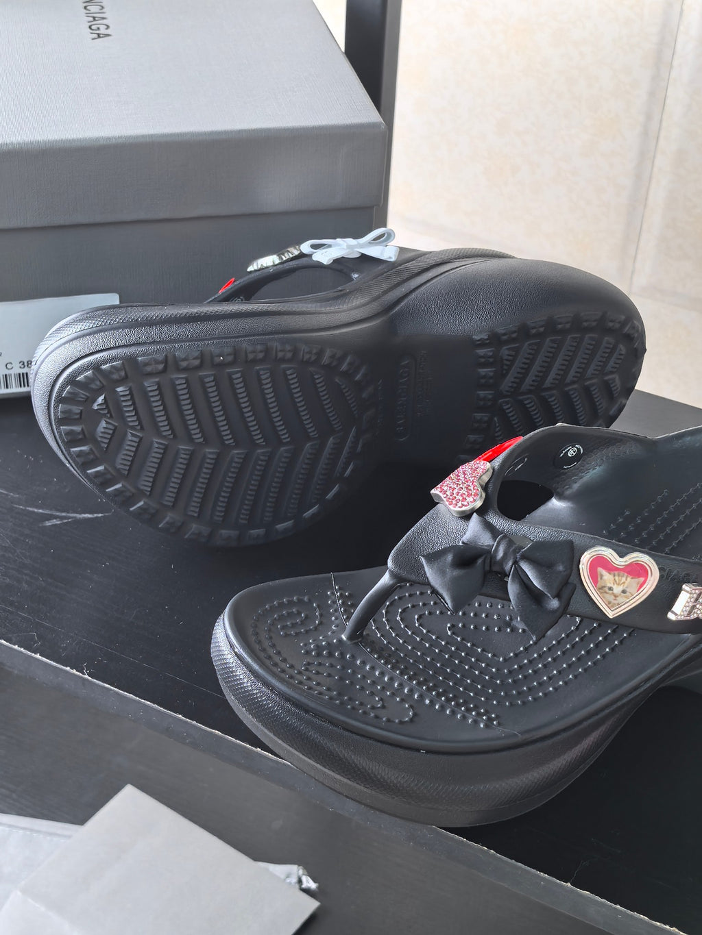 Black platform sandals shown from the side with heart patch and textured sole