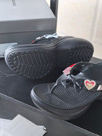 Black platform sandals shown from the side with heart patch and textured sole